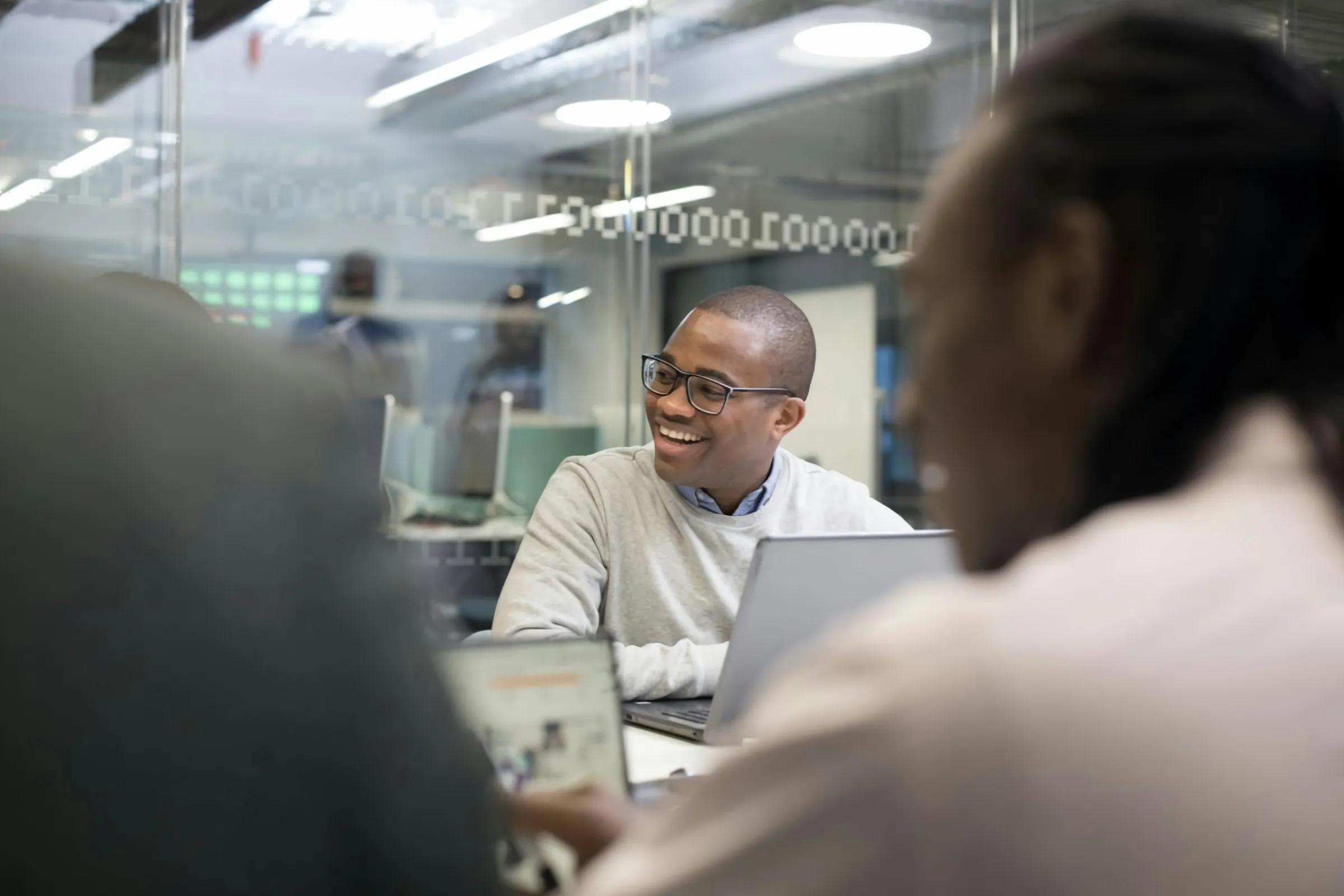 A developer smiling during a working session in a bright open-plan office.